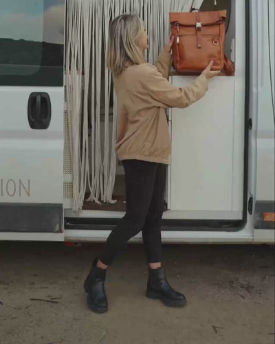 Side view of woman holding vintage leather backpack bag