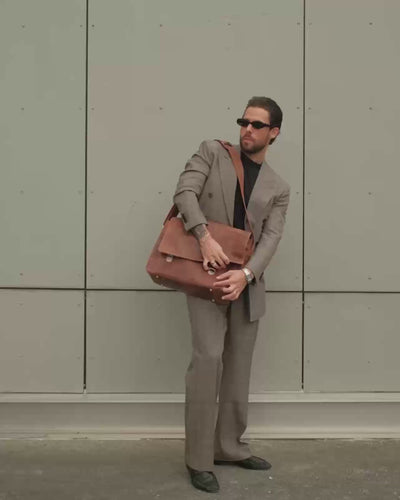 Front view of a camel leather messenger bag worn across the body
