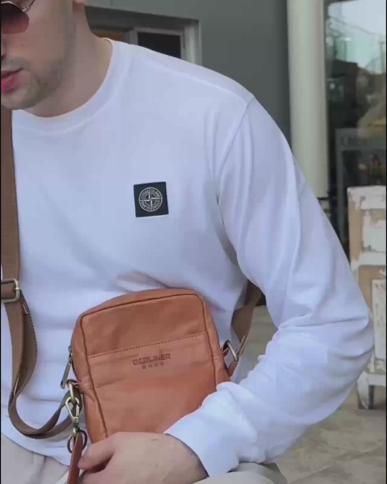 Close up of man wearing a white shirt and a vintage leather messenger bag with a strap